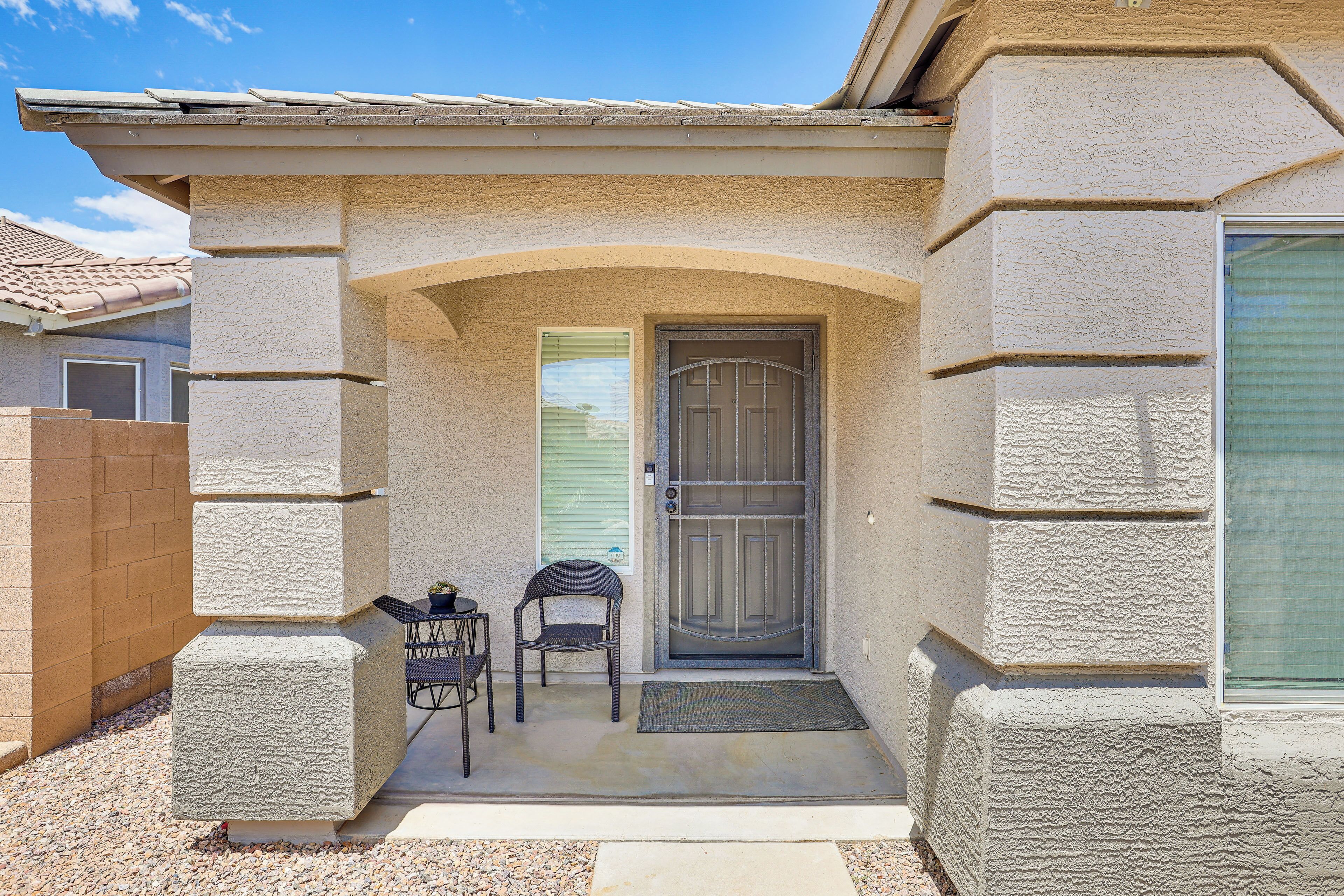 A house with a front porch, a door, and two chairs.