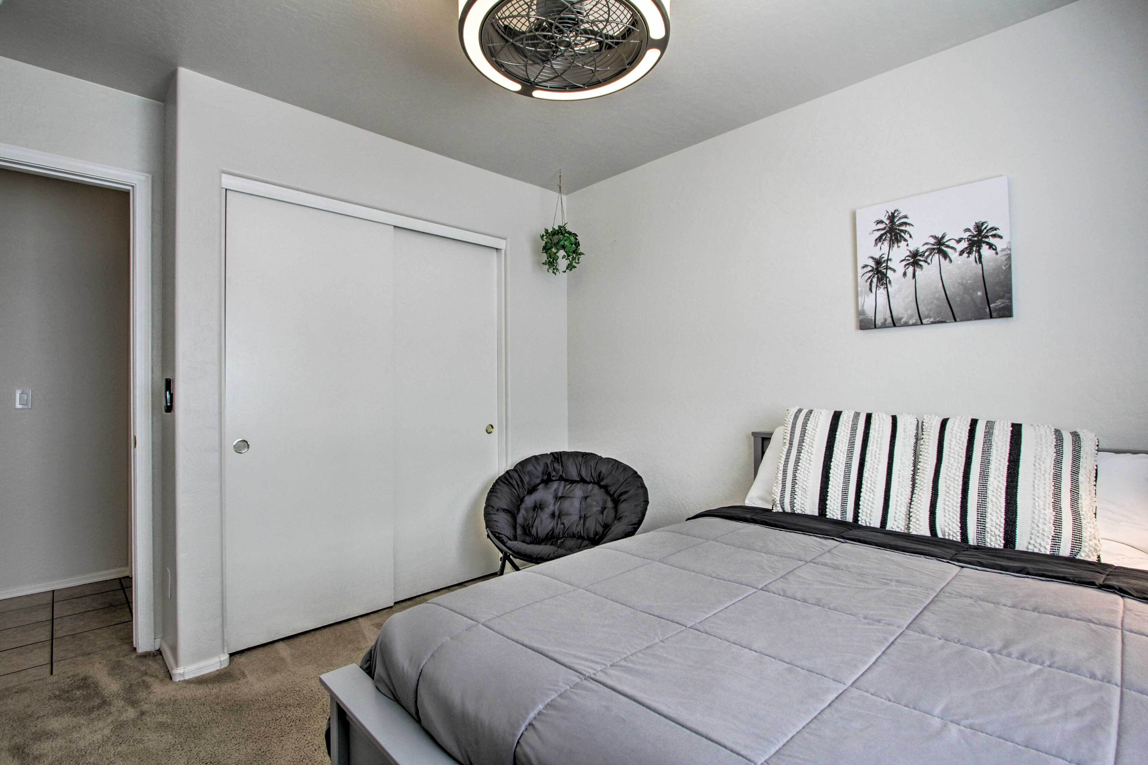 A bedroom with a bed, a chair, a door, and a wall-mounted plant.