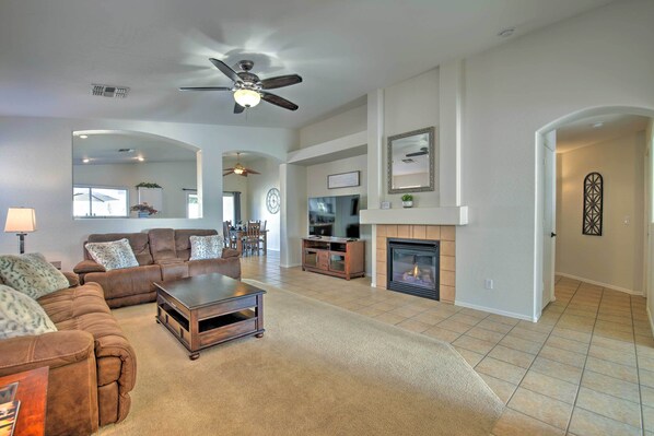 A spacious living room with a sofa set, a coffee table, a fireplace, and a ceiling fan.