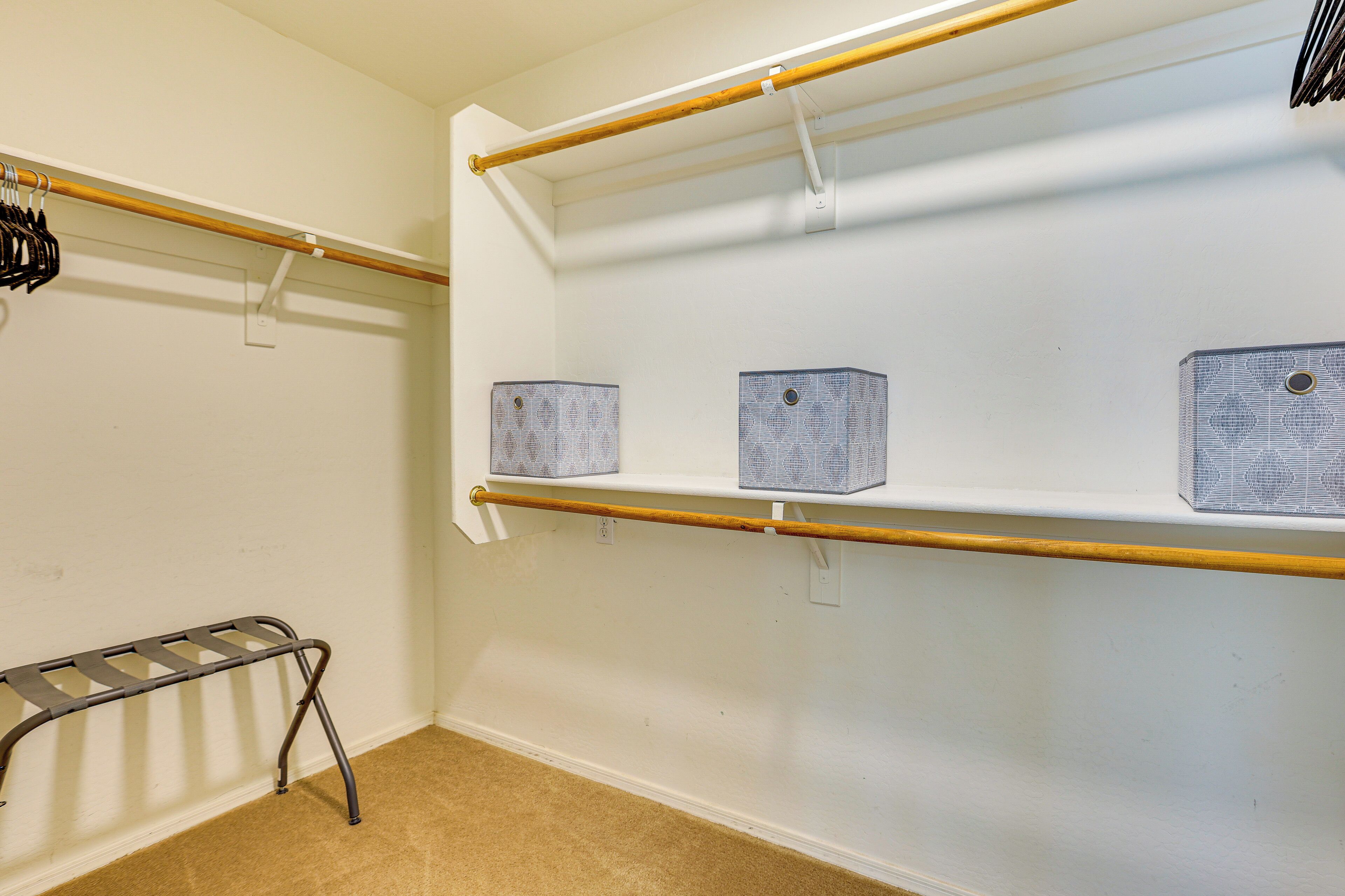 Una habitación con una pared blanca, un perchero de madera y tres cajas de almacenamiento.