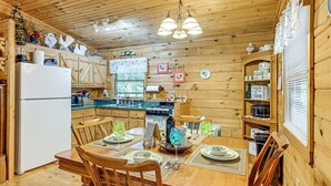 A wooden cabin-style kitchen with a dining table set for two, wooden cabinets, and a refrigerator. - 11 Mi to Dtwn: Franklin Cabin w/ Porch! (Franklin)