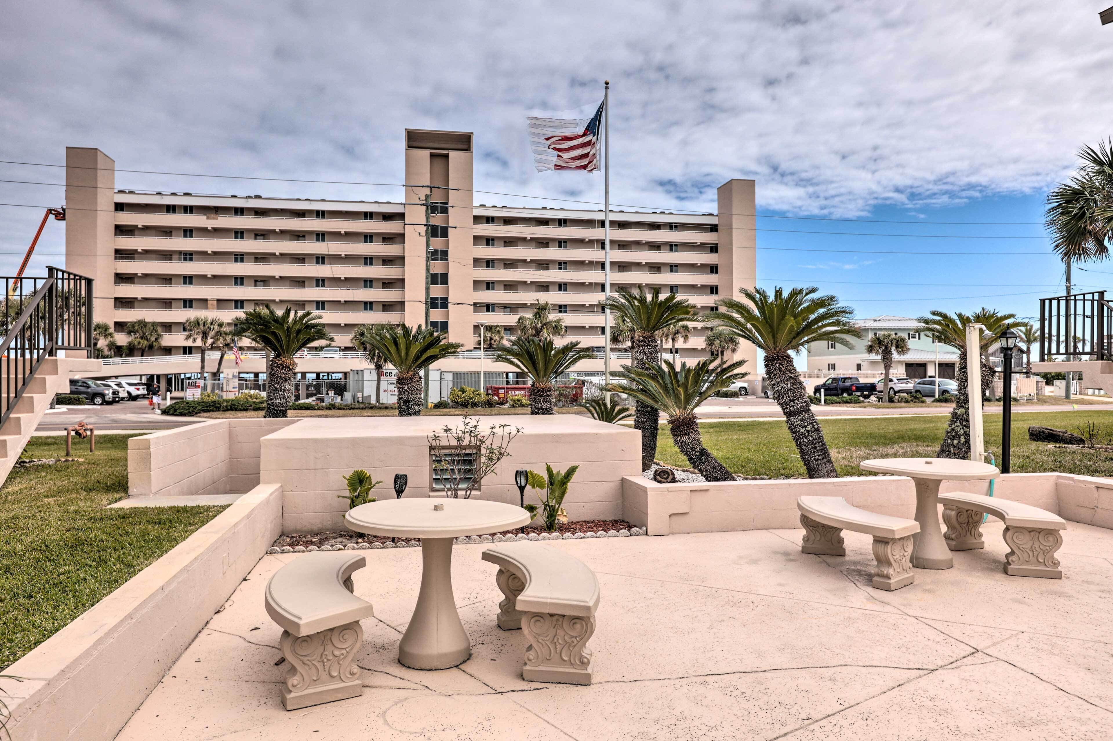 A hotel courtyard with a flag, palm trees, and a seating area.