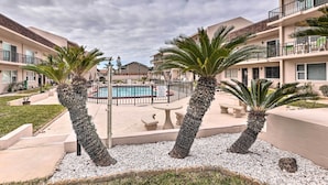 Une cour avec une piscine, des palmiers et un bâtiment doté de balcons.