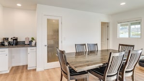 A dining area with a wooden table and chairs, a kitchen with white cabinets, and a window with a view. - Private Pool & Patio: Modern Lake Havasu Home! (Lake Havasu City)