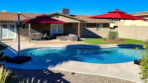 A backyard with a swimming pool, patio furniture, and red umbrellas. - Private Pool & Patio: Modern Lake Havasu Home! (Lake Havasu City)