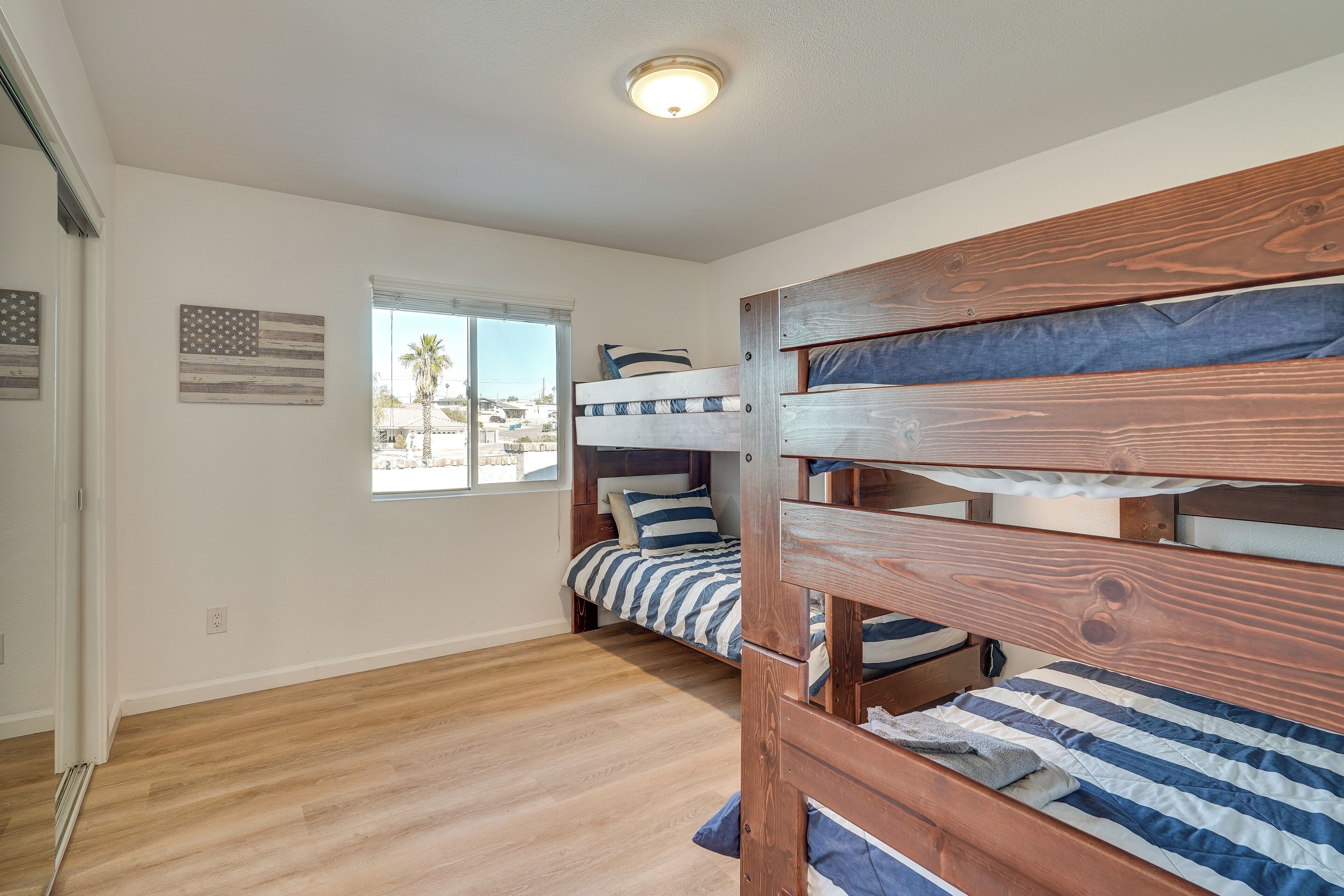 A room with two bunk beds, a window with a view, and an American flag on the wall.