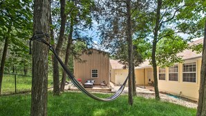 A hammock in a grassy backyard with a wooden deck and a house in the background. - Holiday Island Home: Fire Pit & Boat Parking! (Eureka Springs)