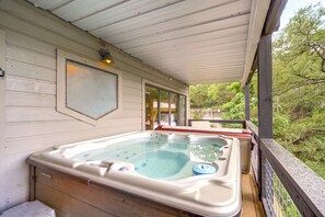 Relax on the outdoor deck with a hot tub and shaded seating area surrounded by lush greenery.