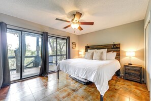 Relax in this serene bedroom with a large bed, ceiling fan, and sliding glass door leading to an outdoor area.