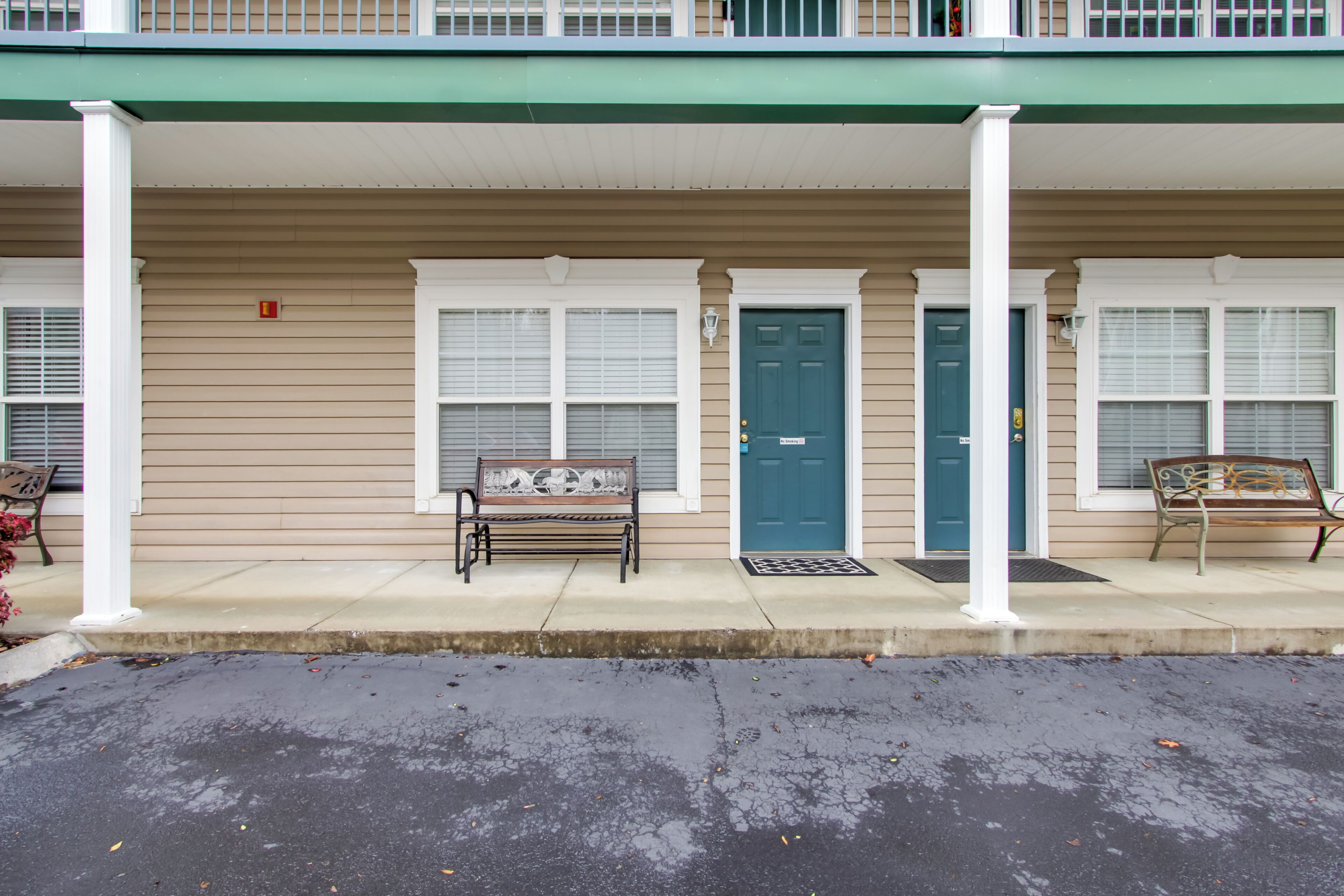 A two-story building with a covered entrance, two doors, and a bench in front.