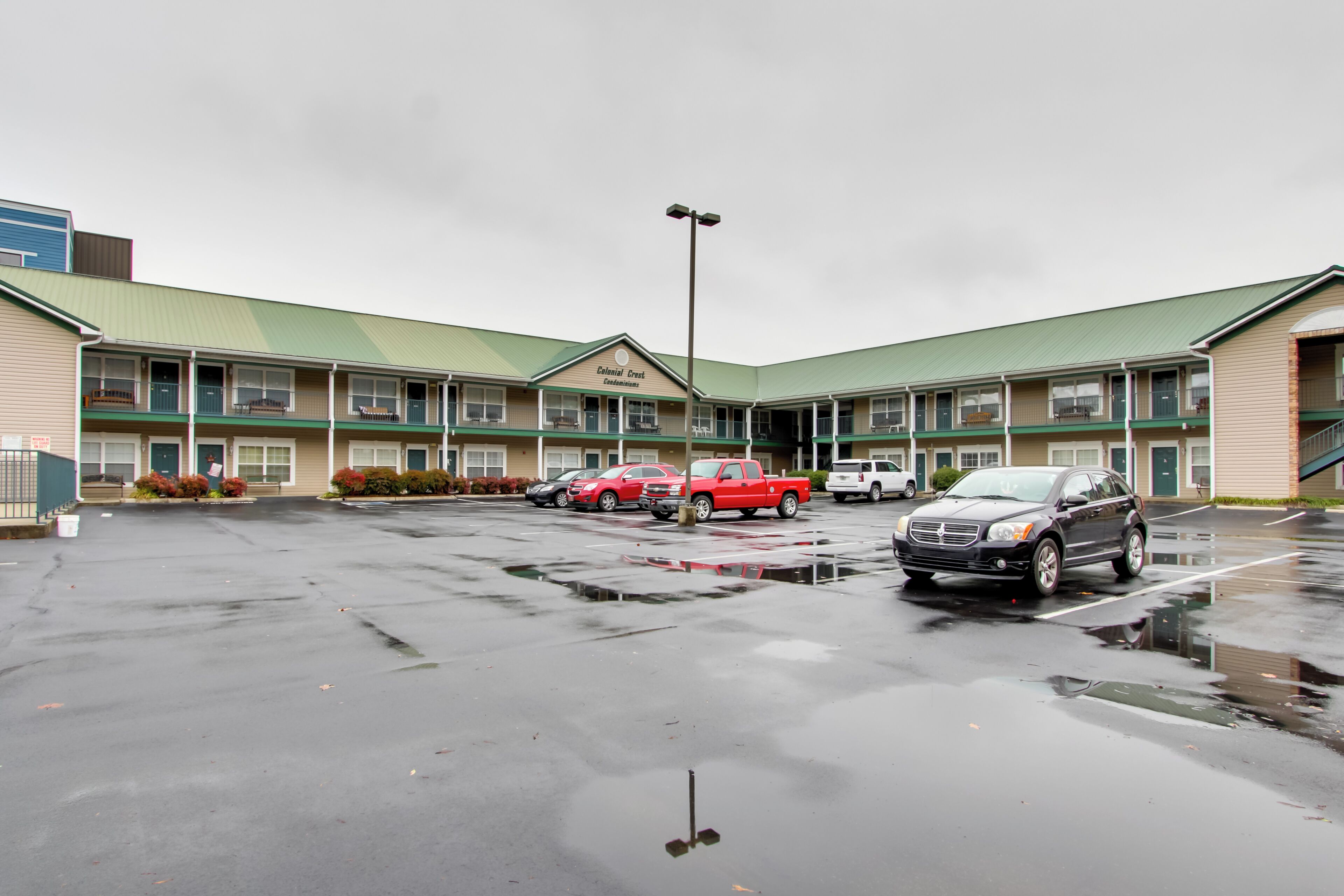Un motel doté d’un toit végétalisé, de nombreuses places de stationnement et de quelques véhicules garés.