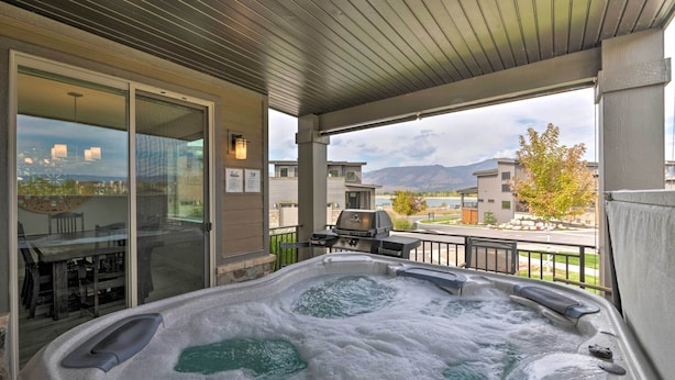A hot tub on a covered patio with a view of a mountain and a barbecue grill. - Modern Huntsville Resort Retreat w/ Deck & Hot Tub (Huntsville)