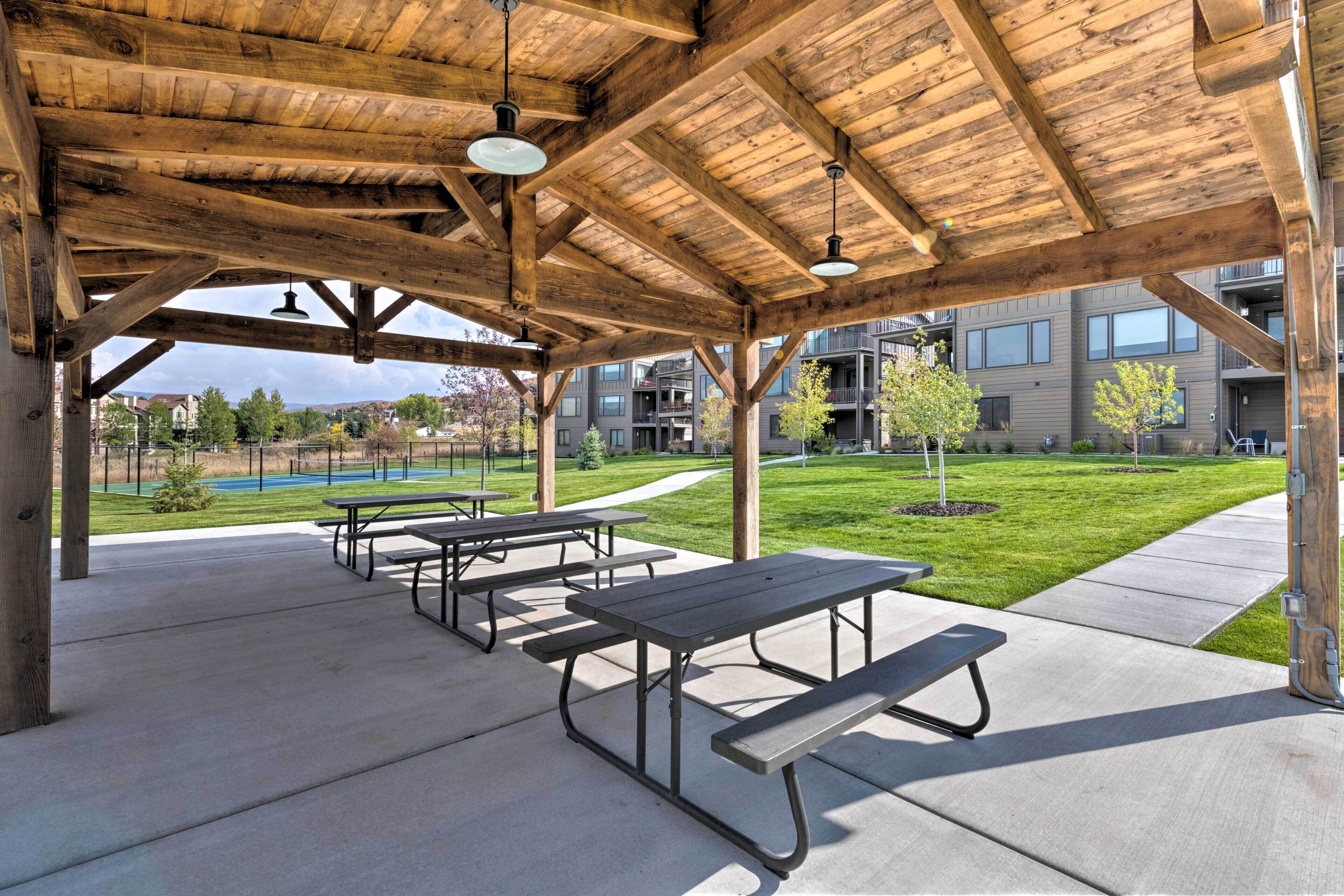 An outdoor covered picnic area with picnic tables and a view of residential buildings in the background.