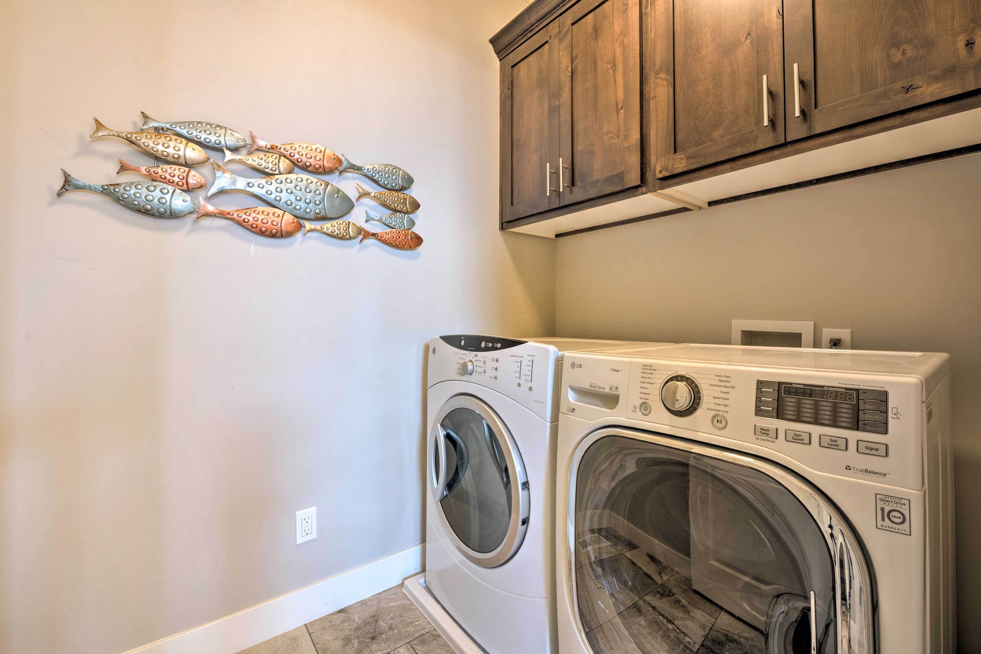 A laundry room with a washing machine and dryer, wooden cabinets, and a wall-mounted fish decoration.