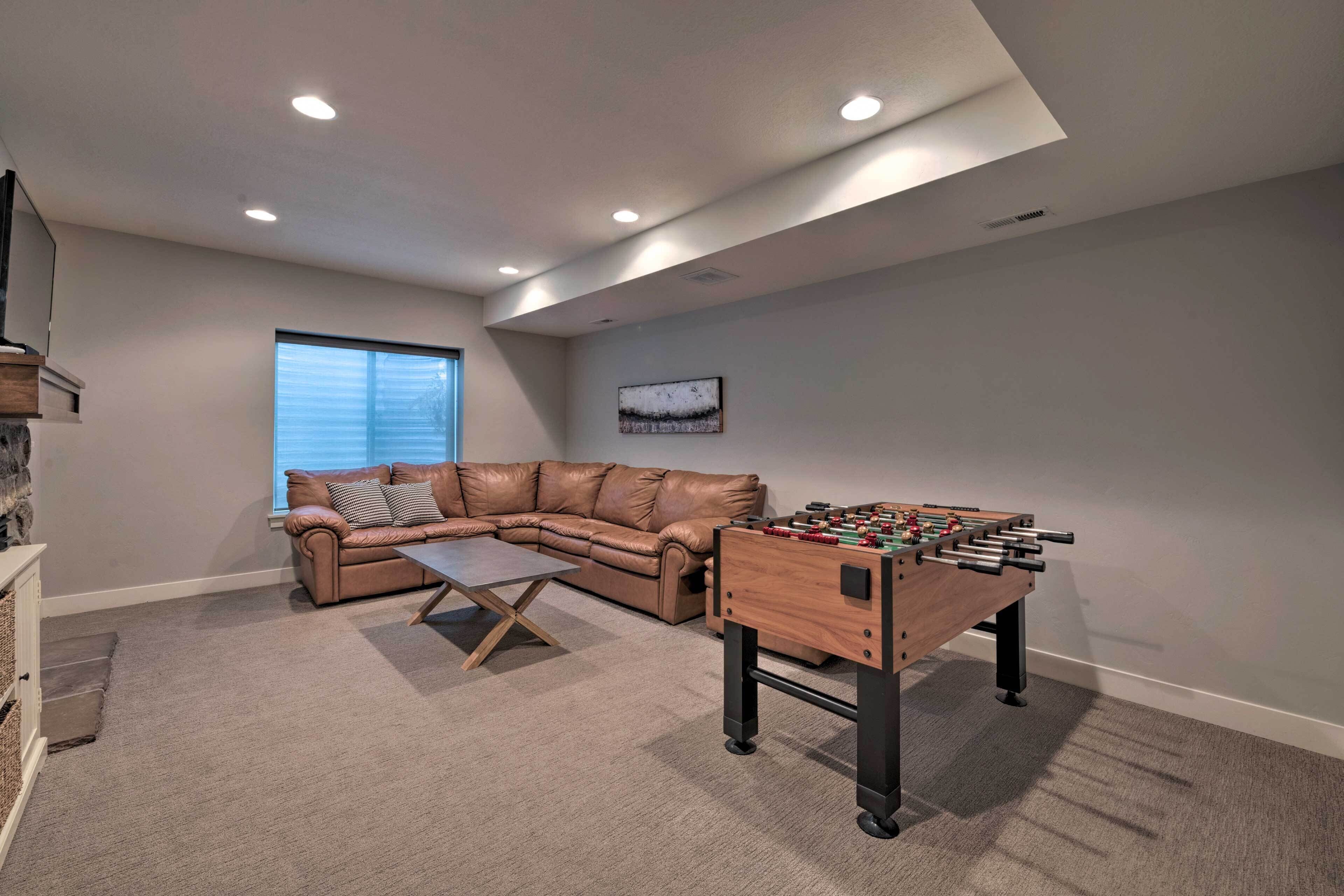 A cozy living room with a leather sofa, a coffee table, and a foosball table.