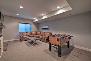 A cozy living room with a leather sofa, a coffee table, and a foosball table. - Modern Huntsville Resort Retreat w/ Deck & Hot Tub (Huntsville)