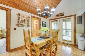 A wooden dining room with a chandelier, wooden chairs, a table with a vase of flowers, and a wooden ceiling. - Branson West Family Cabin Near PGA Golf Course! (Branson West)