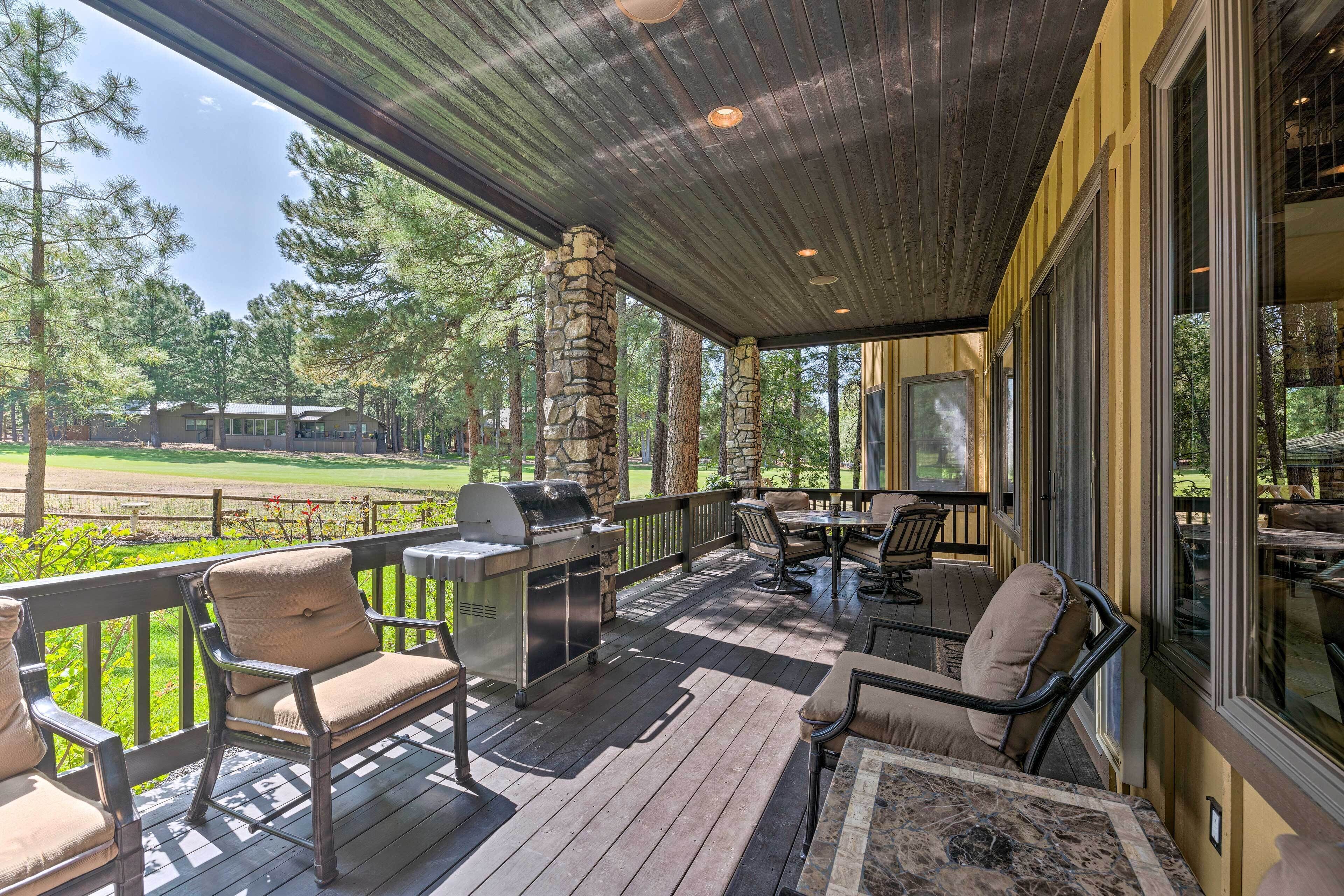 A covered outdoor patio with stone pillars, a grill, and outdoor furniture.