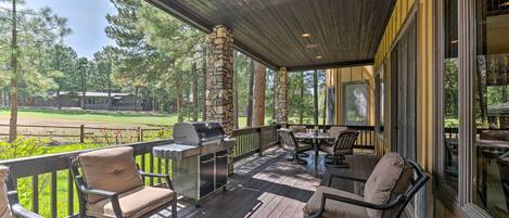 A covered outdoor patio with stone pillars, a grill, and outdoor furniture.