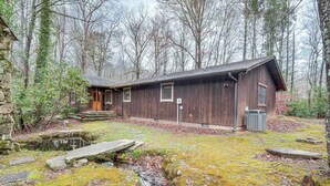 Eine rustikale Holzhütte mit Steinunterbau und einem kleinen Bach im Garten.