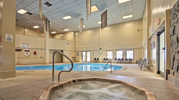 Une piscine intérieure dotée d’un jacuzzi, d’un revêtement de sol carrelé et d’un espace détente avec des chaises.
