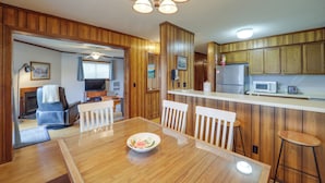 Une cuisine moderne avec des meubles en bois, un coin repas doté d’une table et de chaises en bois, et un ventilateur de plafond.