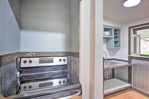 A compact kitchen with a built-in stove, a sink, and a small cabinet with dishes. - Private Beach: Waterfront Disney Getaway! (Disney)