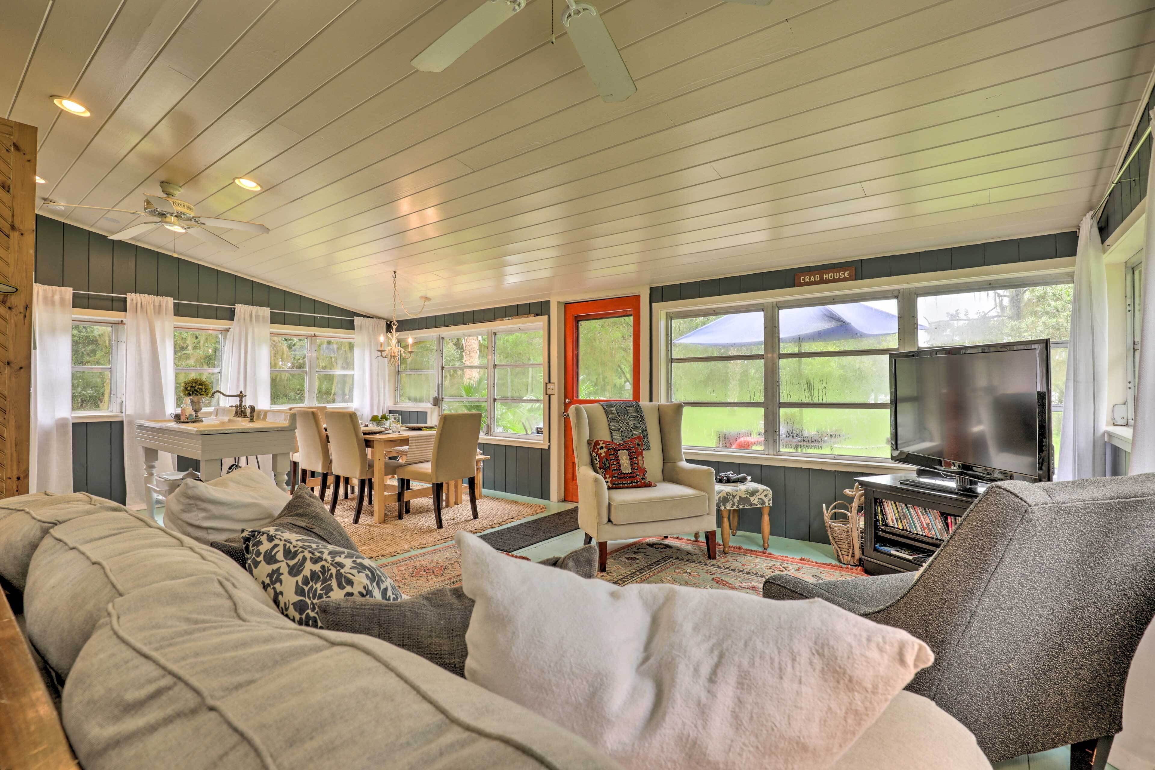 A spacious living room with a large sofa, a television, and a dining area with a table and chairs.