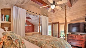 Une chambre à coucher avec un lit à baldaquin, une télévision et un ventilateur de plafond en bois.