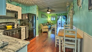 A kitchen with modern appliances, a dining area with a wooden table and chairs, and a living room with a sofa and decorative items. - Beach + Pool Access: Colorful Hilton Head Condo! (Hilton Head Island)