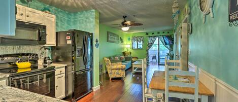 A kitchen with modern appliances, a dining area with a wooden table and chairs, and a living room with a sofa and decorative items.