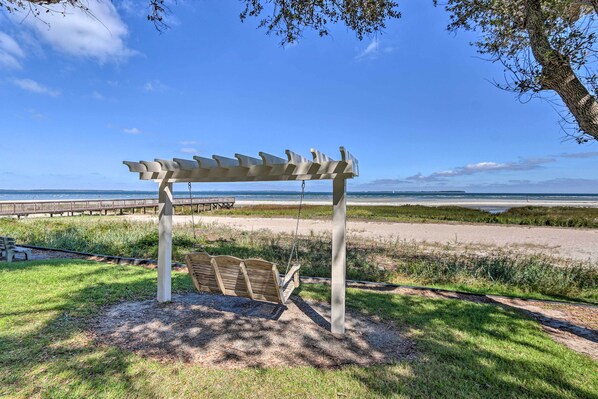 A beachside park with a wooden swing set and a pergola.