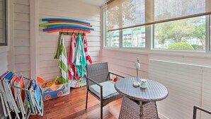 A room with a wicker chair, a small round table, and a window with a view of buildings and trees. - Beach + Pool Access: Colorful Hilton Head Condo! (Hilton Head Island)
