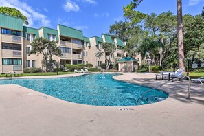 A swimming pool with lounge chairs and a gazebo, surrounded by multi-story buildings with balconies. - Beach + Pool Access: Colorful Hilton Head Condo! (Hilton Head Island)