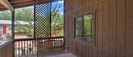 Eine Holzterrasse mit Deckenventilator, Gitterverkleidung und Blick auf eine Wohngegend.