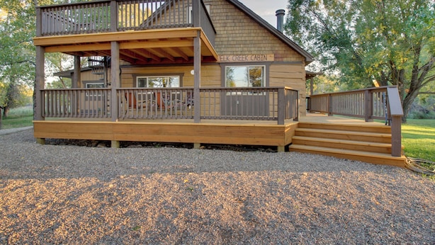 Une cabane dotée d’une terrasse à deux niveaux, d’un porche couvert et d’une cheminée.