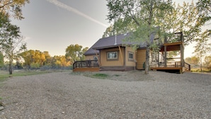 Une maison à deux étages avec une allée en gravier et une terrasse en bois.