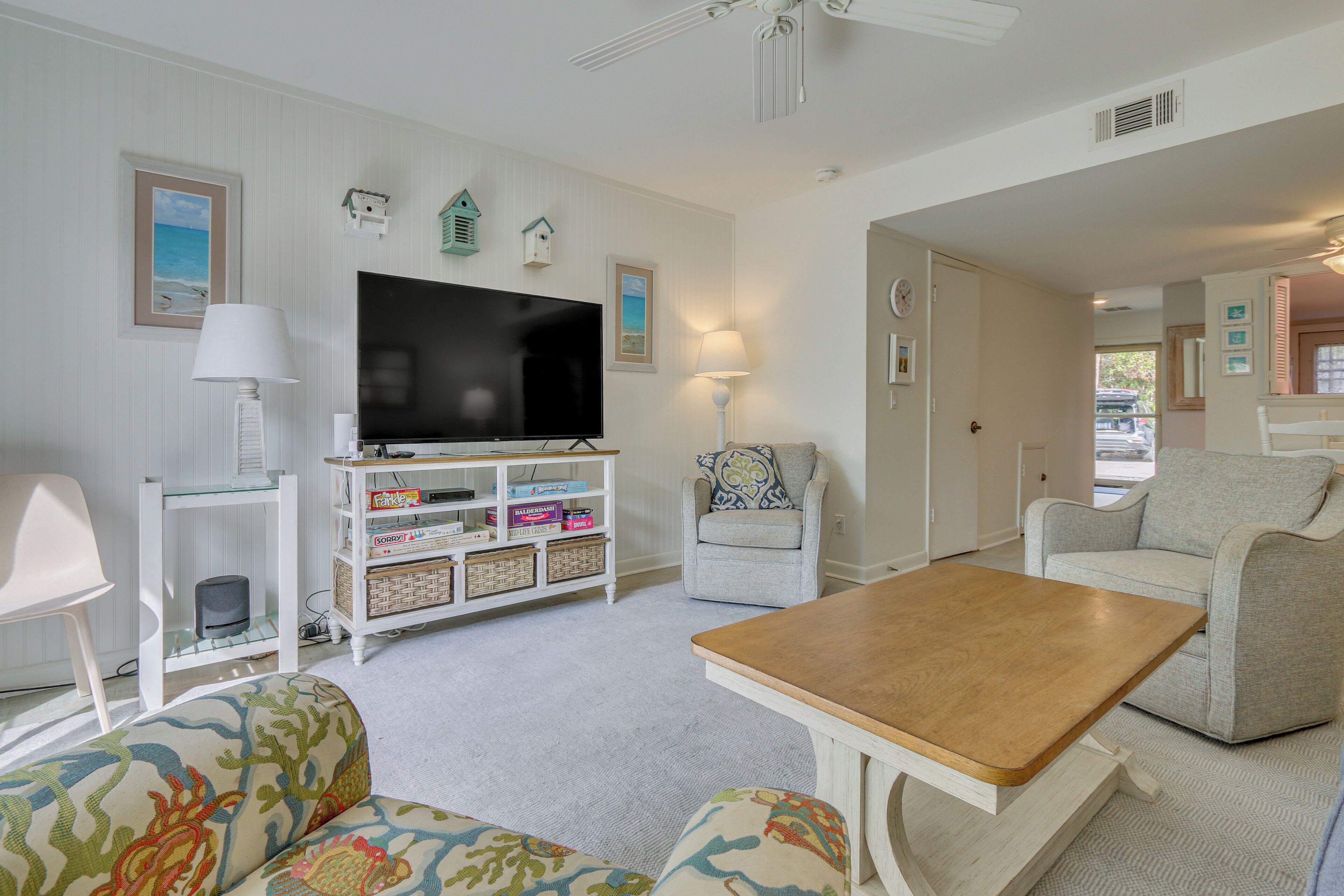 A living room with a television, two armchairs, a coffee table, and a bookshelf.