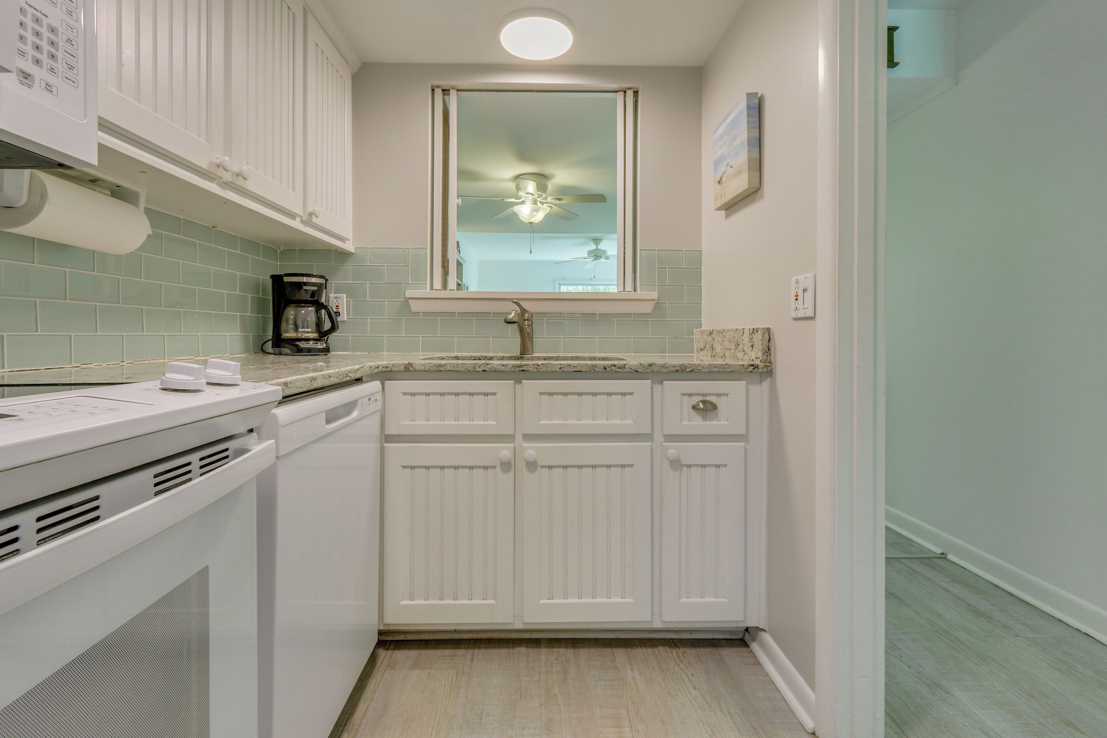 A compact kitchen with white cabinets, a built-in microwave, and a coffee maker.