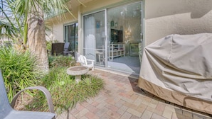 Une terrasse avec un barbecue couvert, une chaise et une petite table.