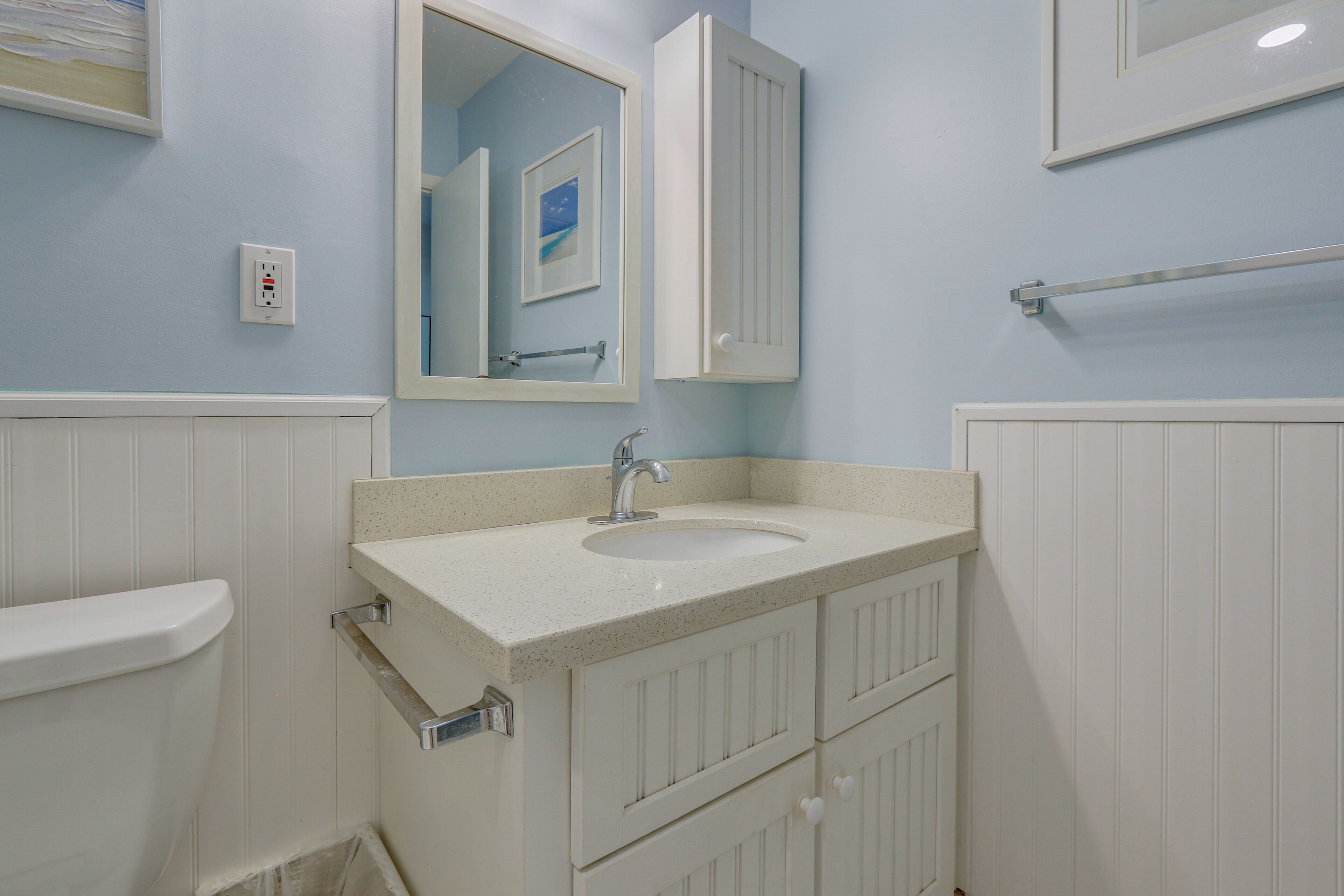 A bathroom with a sink, mirror, cabinet, and towel rack.