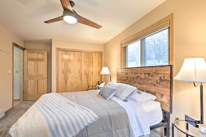 A bedroom with a bed, a ceiling fan, a window, and a nightstand with a lamp. - Cozy Dam Lake Escape w/ Dock, Yard & Water Access! (Eagle River)