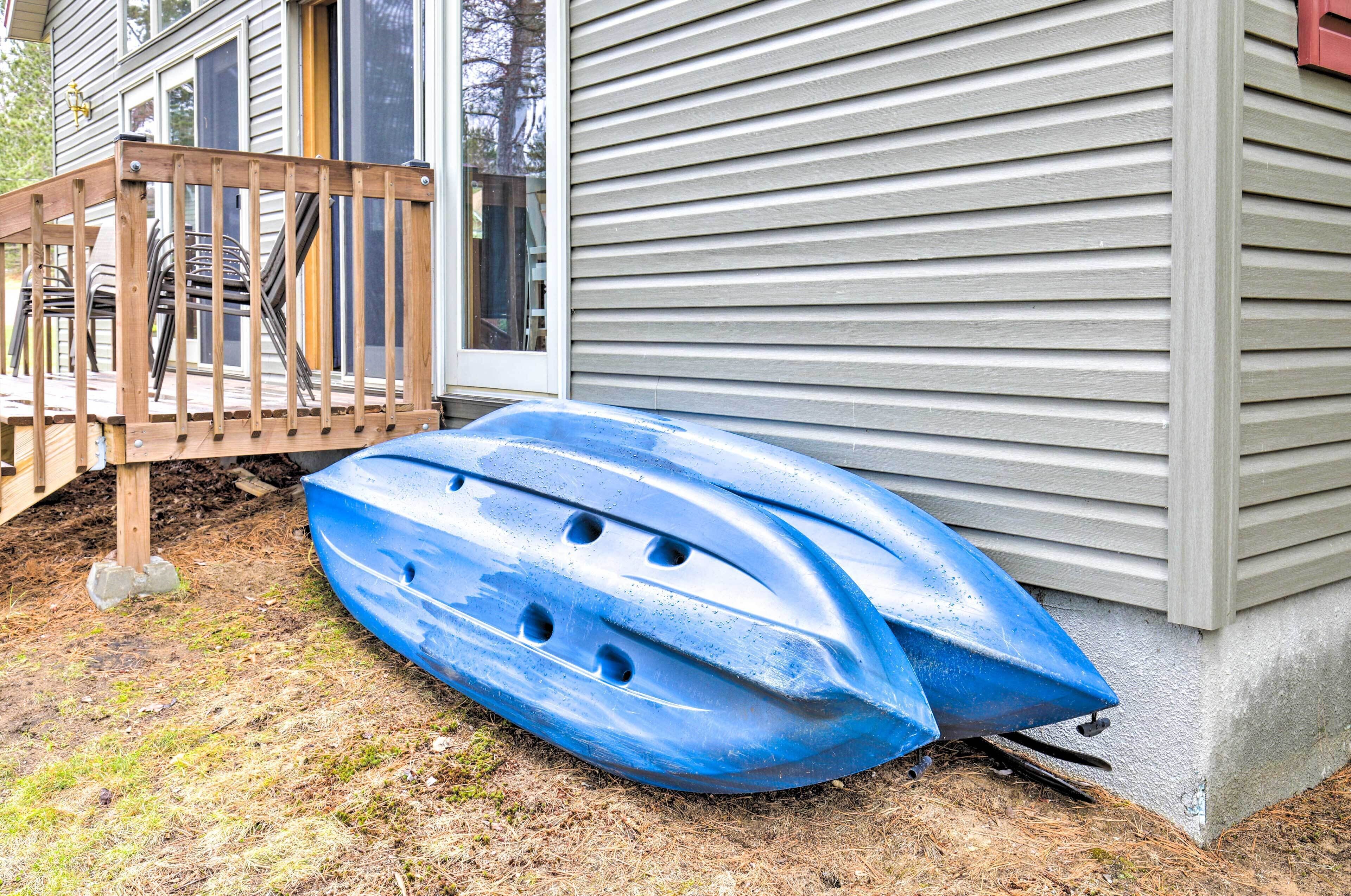 A blue kayak lying on the ground next to a house with a wooden deck.