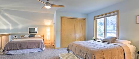 Une chambre avec deux lits, un ventilateur de plafond, une fenêtre et une armoire en bois.