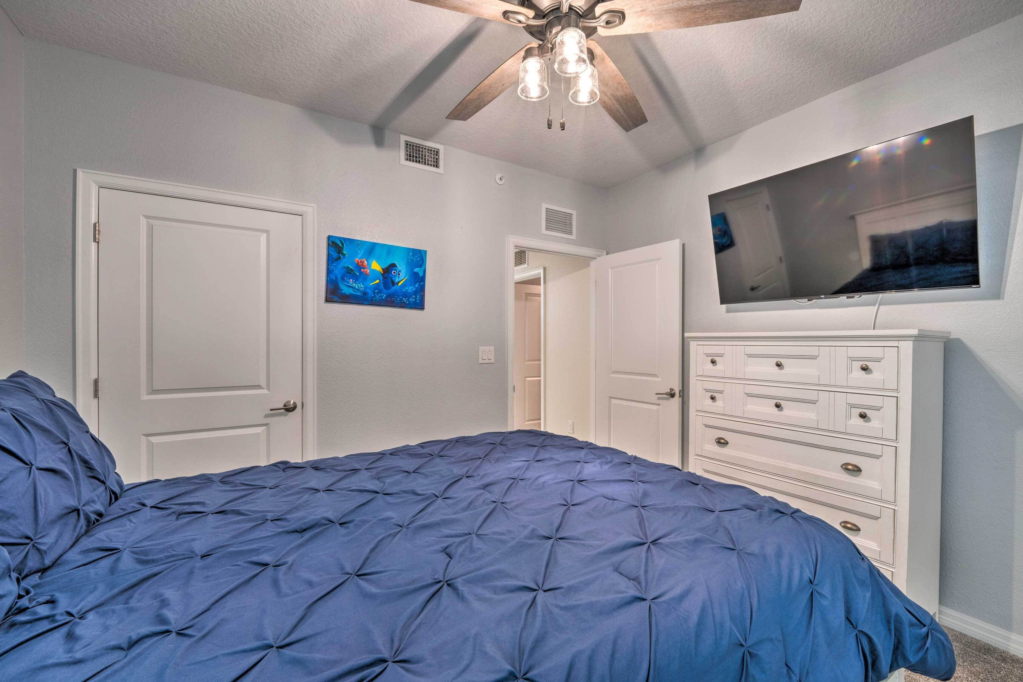 Ein Schlafzimmer mit einem großen Bett, einem Deckenventilator, einem Fernseher und einer Kommode.