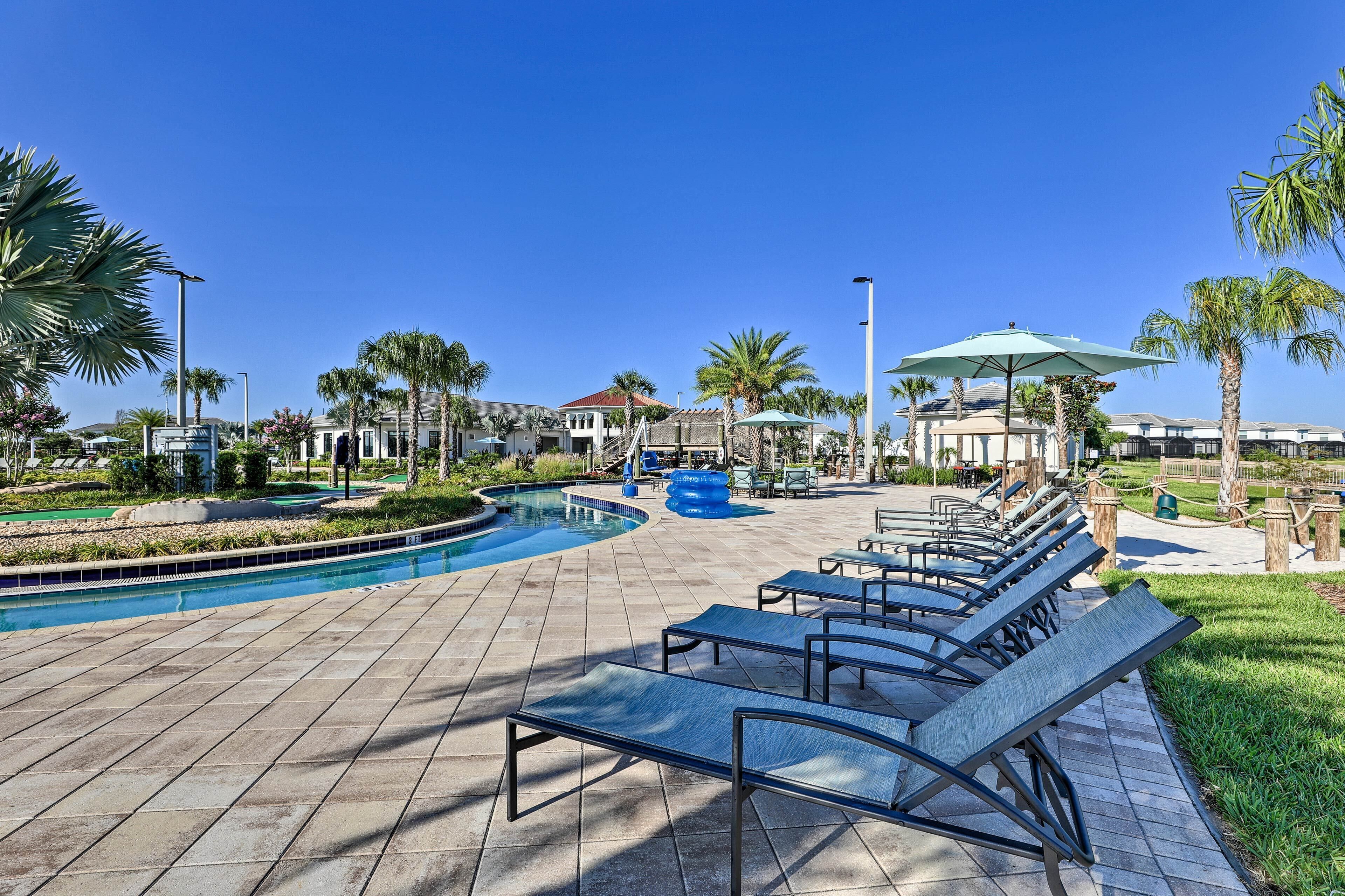 A poolside area with lounge chairs, a pool, and palm trees.