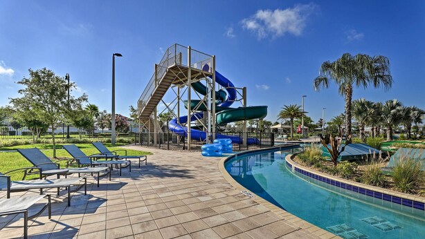 Ein Poolbereich mit Wasserrutsche, Liegestühlen und blauem Himmel.