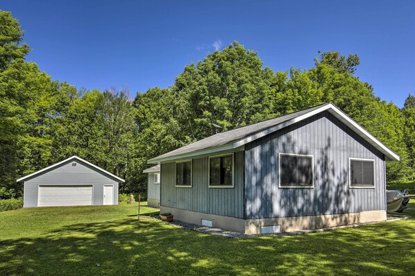 A two-story house with a garage, surrounded by lush greenery and trees. - Cozy Florence Cabin, Proximity to Keyes Peak! (Florence)