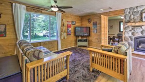 A cozy cabin interior with a wooden sofa, a television, and a stone fireplace. - Cozy Florence Cabin, Proximity to Keyes Peak! (Florence)