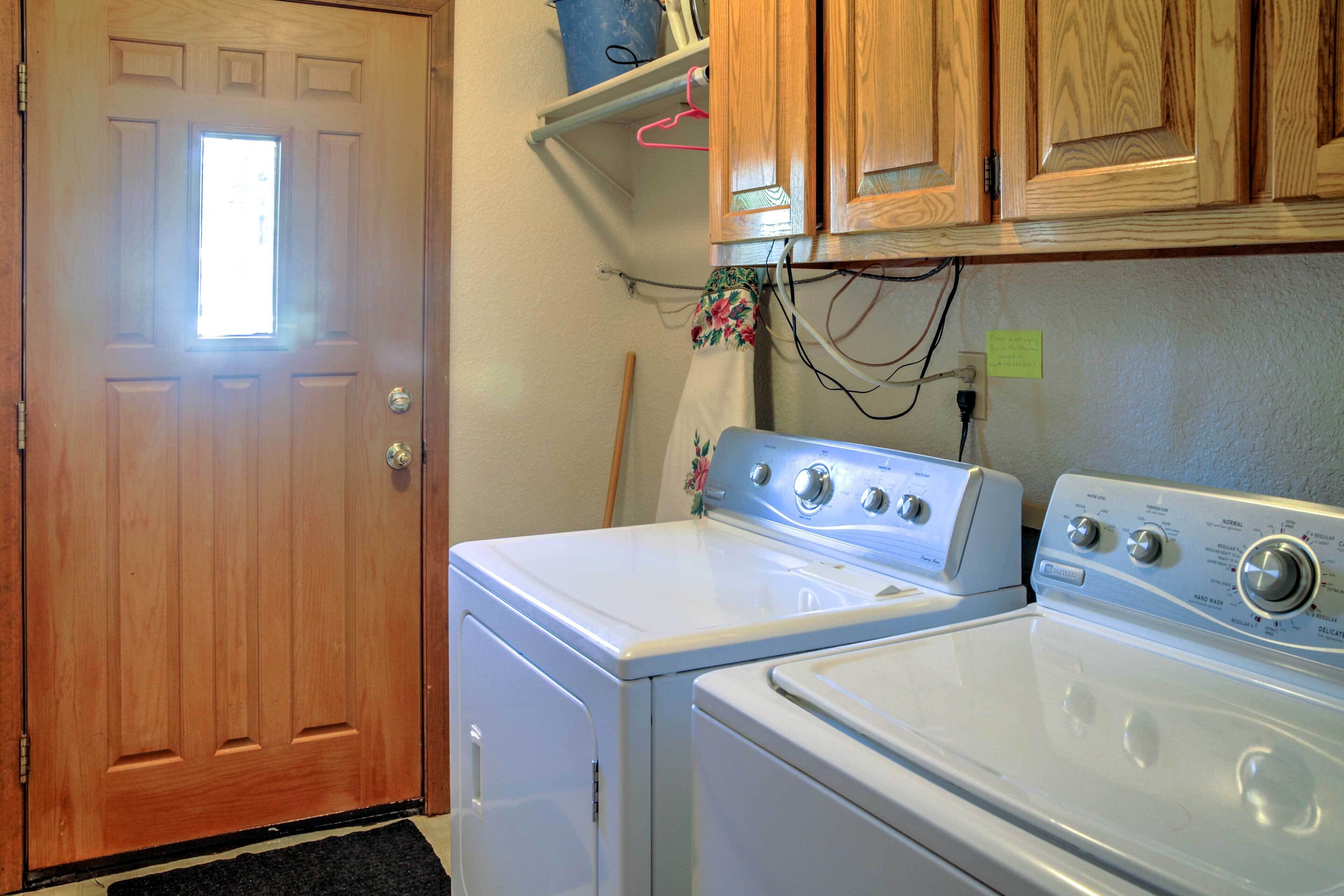 A laundry room with a wooden door, a white washer and dryer, and wooden cabinets above.